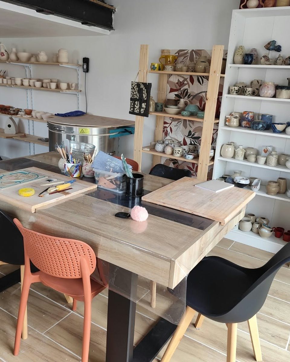 Atelier de céramique Les Mains de Madeleine aux Sables-d'Olonne, table de modelage et étagères de pièces en grès