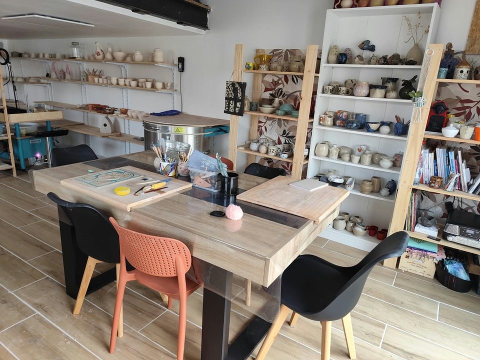 Atelier de céramique Les Mains de Madeleine aux Sables-d'Olonne, table de modelage et étagères de pièces en grès
